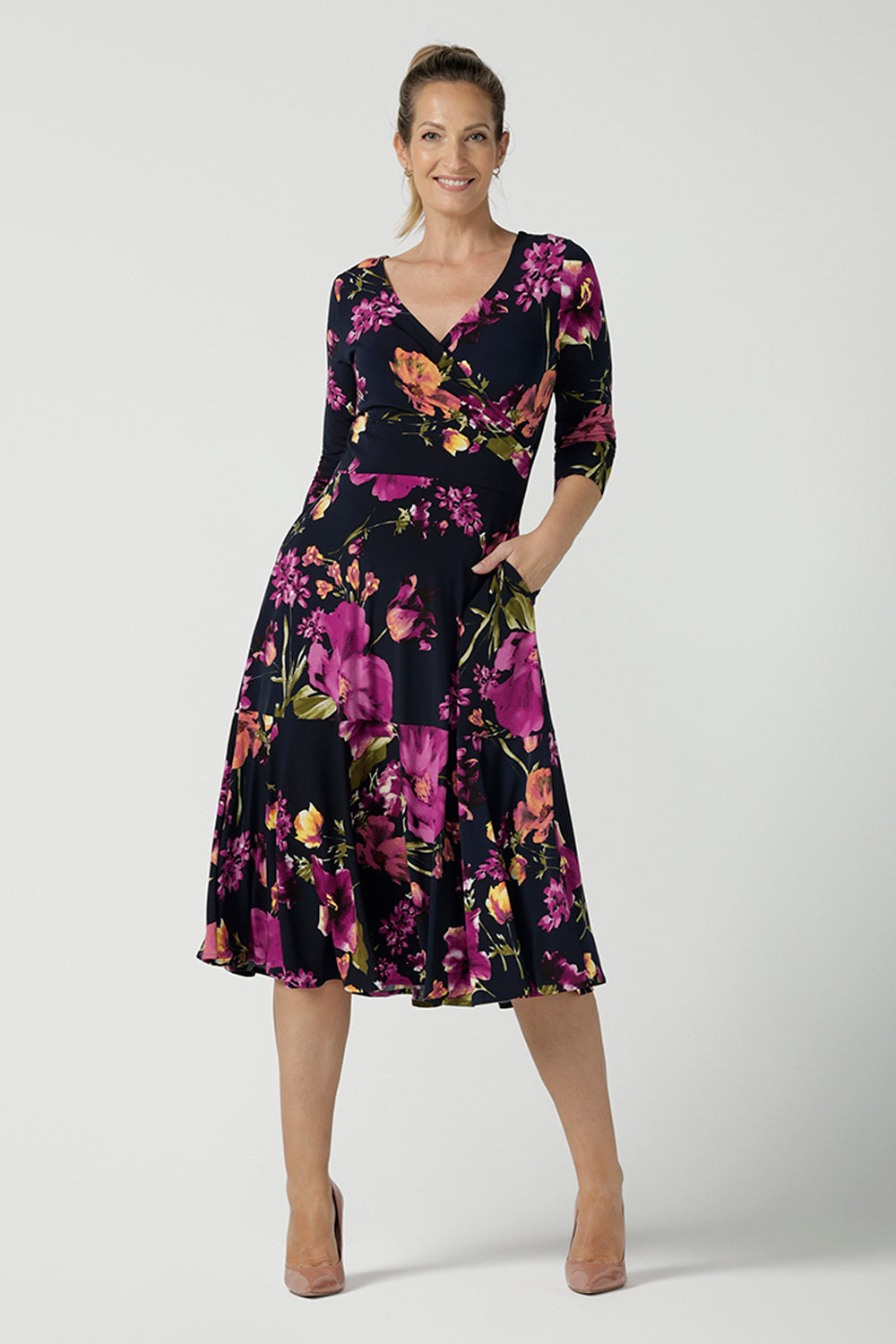A size 10 Woman wears the Bettina Petite Reversible dress the Celeste print. It is a fixed wrap style with pockets and frill detail. A great work to wedding dress for women size 8 - 24.  
