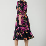 Back view of a size 10 Woman wears the Bettina Petite Reversible dress the Celeste print. It is a fixed wrap style with pockets and frill detail. A great work to wedding dress for women size 8 - 24.