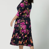 Back view of a size 18 Woman wearing the Bettina Petite Reversible dress the Celeste print. It is a fixed wrap style with pockets and frill detail. A great work to wedding dress for women size 8 - 24.