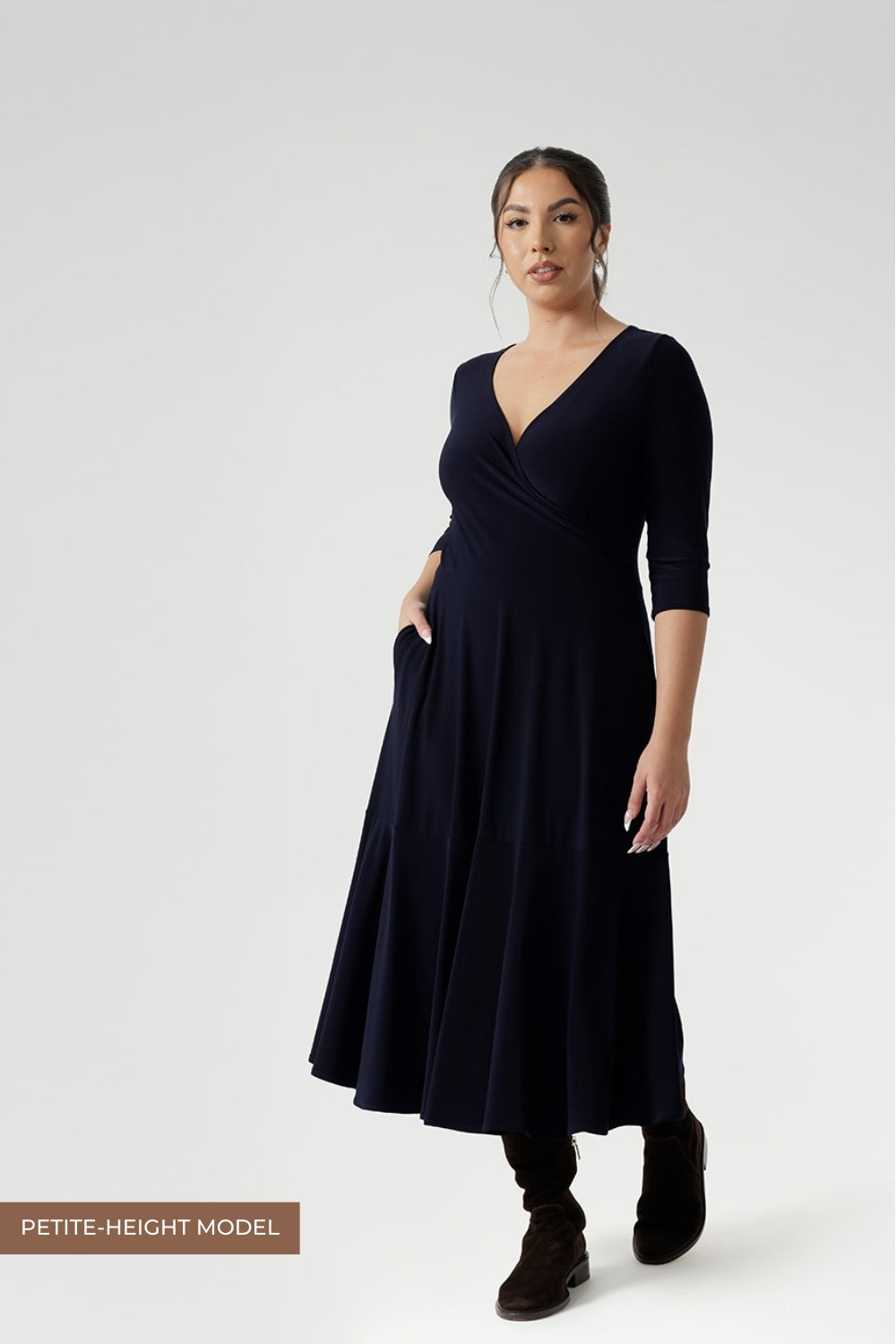 Workwear dress worn by size 10 petite height woman in Navy dry touch jersey. Stylish workwear dresses for women. Midi length with functional pockets, and can be reversed for a choice of v neckline or boat neck. Made in Australia for women size 8 - 24.