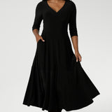 Over 30's woman wears Bettina Reversible Dress in Black. Australian made Jersey fixed wrap dress features a V-neck style with pockets and midi length. Made in Australia for women size 8-24. Reversible dress can be worn featuring both a boat neck or Vneck.