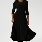 Size 10 woman wears Bettina Reversible Dress in Black. Australian made Jersey fixed wrap dress features a V-neck style with pockets and midi length. Made in Australia for plus size women and petite height women sizes 8-24. Dress worn with boat neck front facing and styled with long boots.