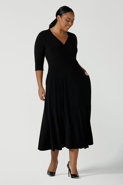 Size 16 woman wears a black reversible Bettina dress in black. V-neck style with pockets and midi length. Made in Australia for women size 8 - 24. 