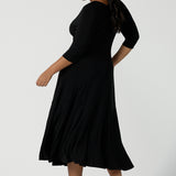 Back view of a size 16 woman wears a black reversible Bettina dress in black. V-neck style with pockets and midi length. Made in Australia for women size 8 - 24.