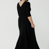 Back view of size 10 woman wearing a black reversible dress. Black jersey dress with black heels. Made in Australia for women size 8 - 24. Comfortable easy care jersey. Made in Australia for women size 8 - 24.