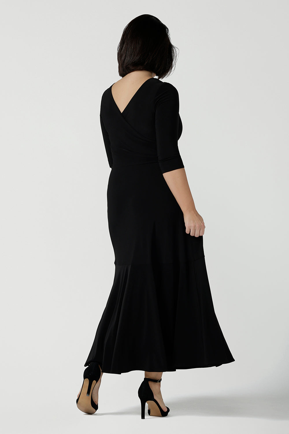 Back view of size 10 woman wearing a black reversible dress. Black jersey dress with black heels. Made in Australia for women size 8 - 24. Comfortable easy care jersey. Made in Australia for women size 8 - 24.