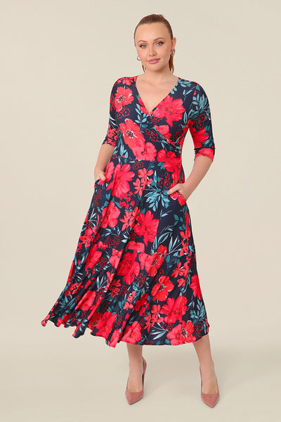 A size 12 woman wears a reversible wrap dress with 3/4 sleeves. Featuring a midi-length skirt with ruffle hem and 3/4 length sleeves, this floral printed jersey dress is worn with a V-neckline and wears well as a work dress or everyday dress.