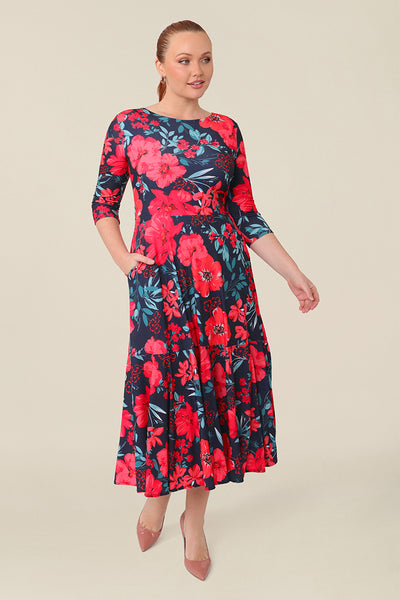 A size 12 woman wears a reversible wrap dress with 3/4 sleeves. Featuring a midi-length skirt with ruffle hem and 3/4 length sleeves, this floral printed jersey dress is worn with a boat neckline and wears well as a work dress or everyday dress. s a work dress or everyday dress.