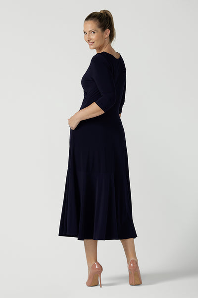 Back view of a size 10 woman wears a Bettina Reversible dress in Navy. Stylish workwear for women. Midi length with functional pockets. Made in Australia for women size 8 - 24. Soft Navy jersey fabric.