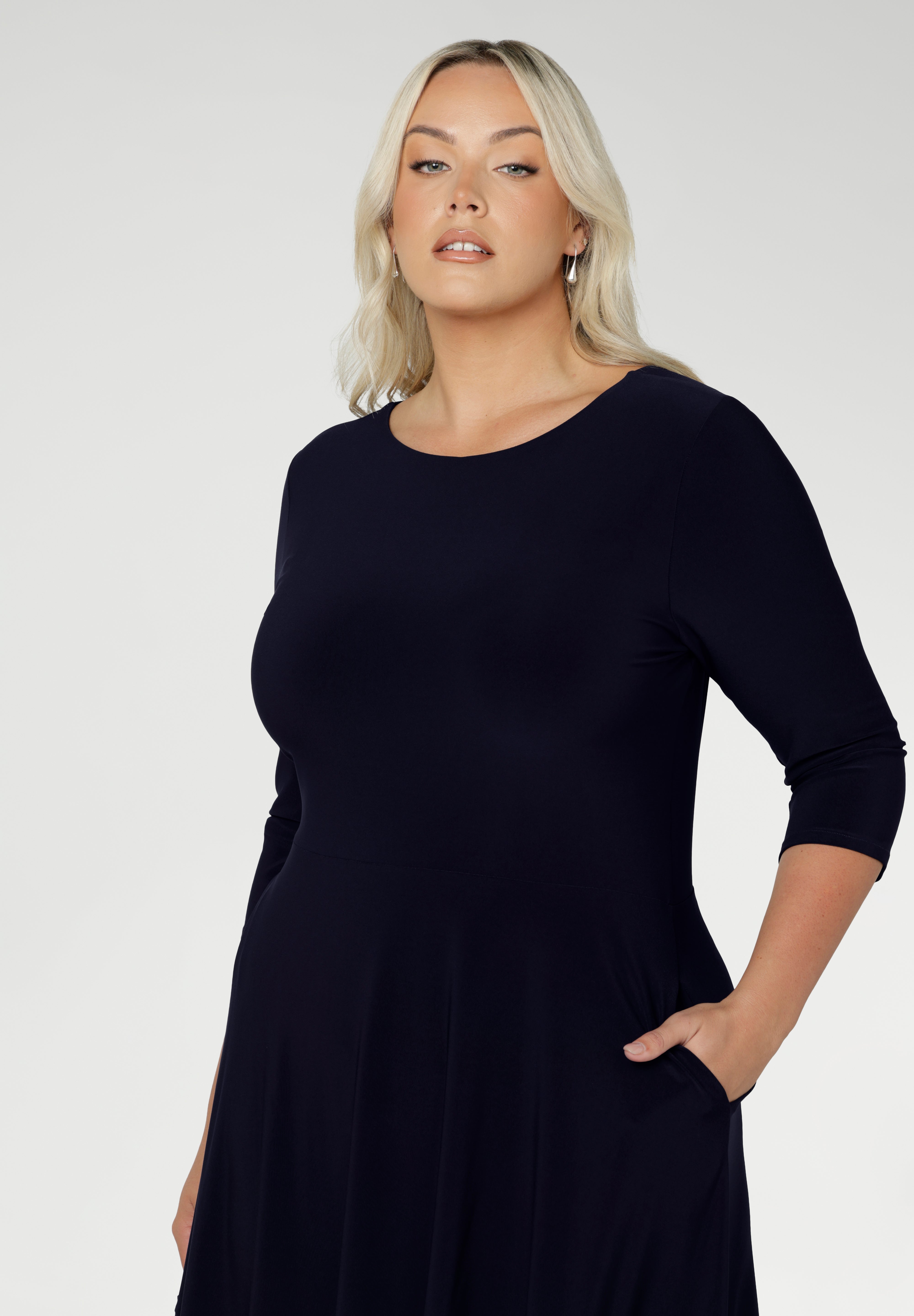 Close up of a size 18 woman wears a Bettina Reversible dress in Navy. Stylish workwear for women. Midi length with functional pockets. Made in Australia for women size 8 - 24. Soft Navy jersey fabric.