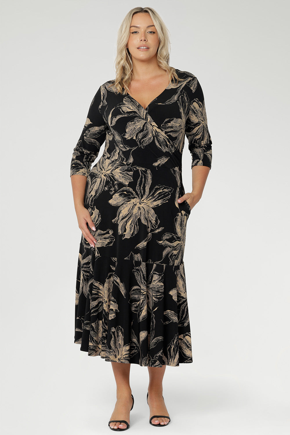 The fully reversible design offers two sophisticated neckline options: a fixed wrap V-neck on one side and a classic boat neckline with a subtle V-shaped back on the other, giving you two distinct looks in one. Size 10 woman wears reversible dress with V neck line front facing.