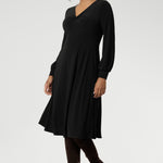 The Bianca Dress is a versatile wardrobe essential, designed to take you from work to events with effortless elegance. This classic black knee-length dress features a flattering V-neckline and a twist-front bodice that enhances your shape, while the cuffed long sleeves add a polished finish.