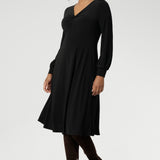 The Bianca Dress is a versatile wardrobe essential, designed to take you from work to events with effortless elegance. This classic black knee-length dress features a flattering V-neckline and a twist-front bodice that enhances your shape, while the cuffed long sleeves add a polished finish.