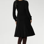 Featuring a sophisticated V-neckline with a twist-front bodice and cuffed long sleeves, it creates a flattering silhouette with elegant detail.