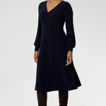The Bianca Dress in Navy is a timeless black knee-length style designed for both work and special occasions. Featuring a sophisticated V-neckline with a twist-front bodice and cuffed long sleeves, it creates a flattering silhouette with elegant detail.