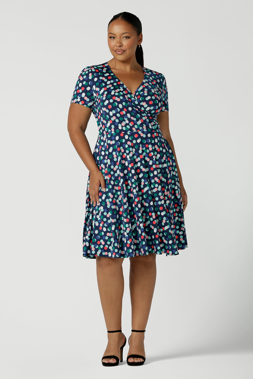 Curvy size 16 woman wears a Bubbles printed Jersey dress with a fixed wrap in a midi length. Styled back with a black heel. Perfect for work to weekend looks. Made in Australia for women size 8 - 24.