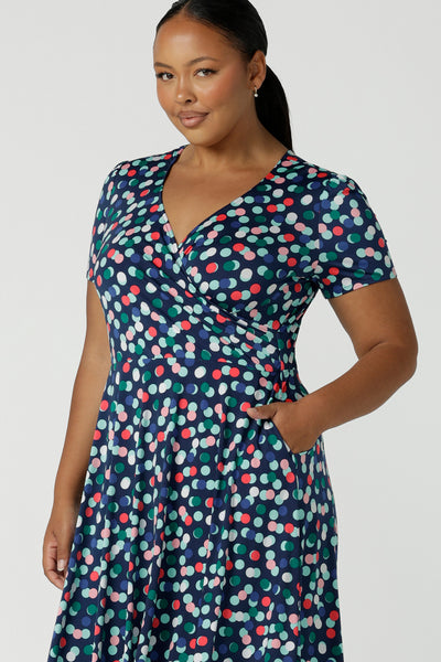 Close up of a curvy size 16 woman wears a Bubbles printed Jersey dress with a fixed wrap in a midi length. Styled back with a black heel. Perfect for work to weekend looks. Made in Australia for women size 8 - 24.