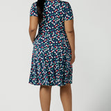 Back view of a curvy size 16 woman wears a Bubbles printed Jersey dress with a fixed wrap in a midi length. Styled back with a black heel. Perfect for work to weekend looks. Made in Australia for women size 8 - 24.