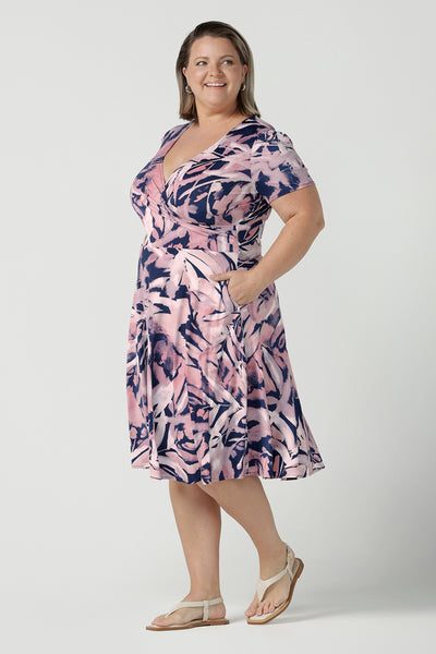 Size 18 curvy woman wearing the Alexis dress in Cantata. A navy base with pink brush strokes print. The perfect work to weekend or wedding guest outfit. Styled back with leather flats. Made in Australia for women size 8 - 24.