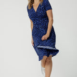 Showing a the full, knee length skirt of an animal print wrap dress, a size 12 woman twirls her skirt. A good wrap dress for summer, this is a short sleeve fixed wrap dress. Shop wrap dresses Australia online at Leina & Fleur in sizes 8-24, petite to plus sizes.