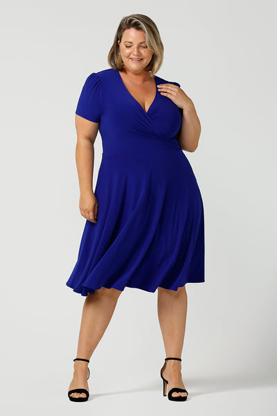 A size 18 woman wears a plus size jersey dress with short sleeves. In cobalt blue jersey, this dress is a good casual dress for weekend wear capsule wardrobes. Shop Australian-made wrap dresses for work online is sizes 8 to 24.