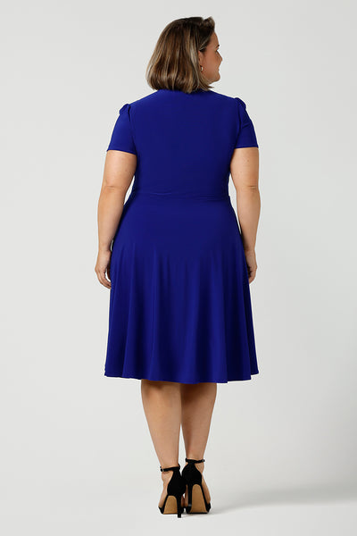 Back view of A size 18 woman wears a plus size jersey dress with short sleeves. In cobalt blue jersey, this dress is a good casual dress for weekend wear capsule wardrobes. Shop Australian-made wrap dresses for work online is sizes 8 to 24.