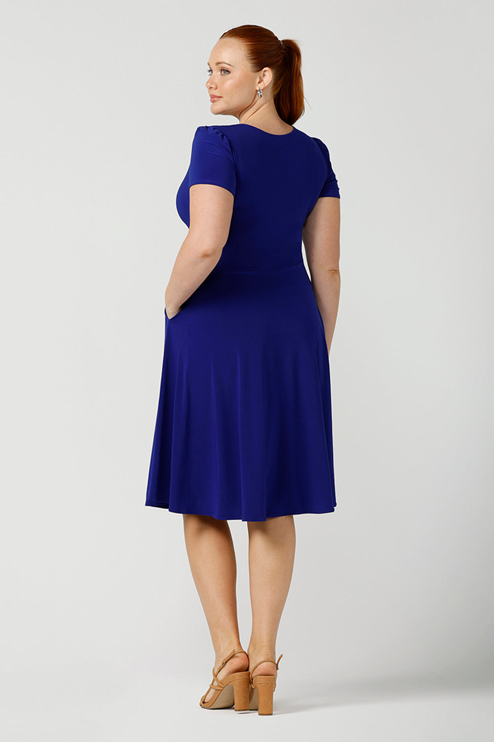 Back view of  A size 12, fuller figure woman wears a jersey dress with short sleeves. In cobalt blue jersey, this dress is a good casual dress for weekend wear capsule wardrobes. Shop Australian-made dresses online is sizes 8 to 24.