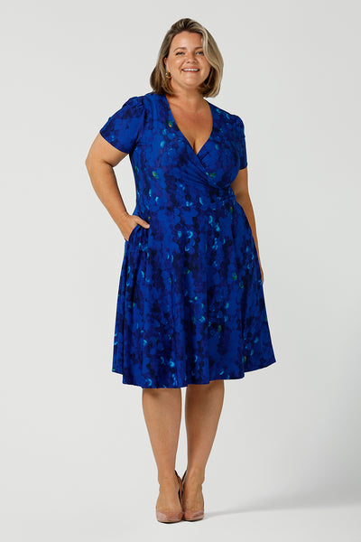 A plus size 18 woman, wearing a chic dress for plus size and fuller figure women, this V-neck dress with 3/4 sleeves comes in a cobalt abstract spotted print and has a knee-length skirt, this dress is good for casual weekend wear.