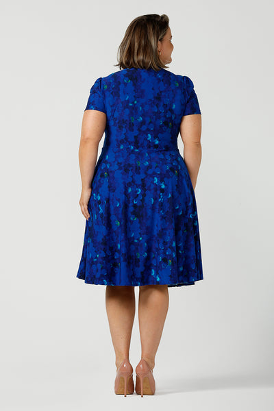 Back view of a plus size 18 woman, wearing a chic dress for plus size and fuller figure women, this V-neck dress with 3/4 sleeves comes in a cobalt abstract spotted print and has a knee-length skirt, this dress is good for casual weekend wear.