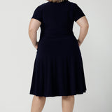 Back view of a Fixed Wrap Bibi dress in Navy. Curvy size 18 woman wears a jersey dress the perfect corporate comfortable work dress. Below the knee length. Size 8 - 24.