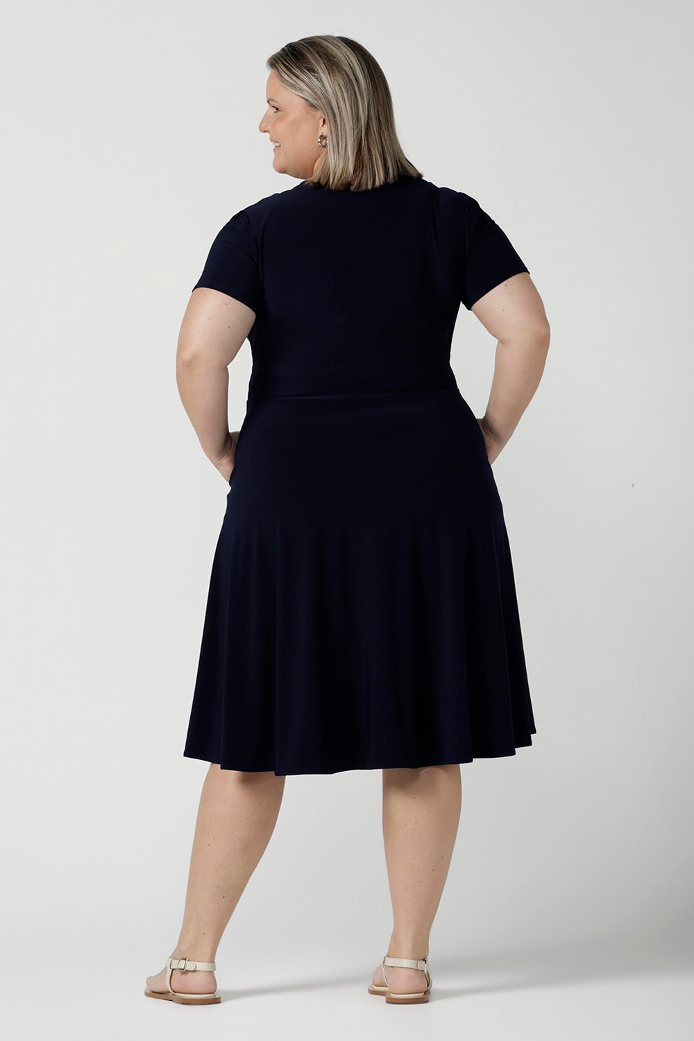 Back view of a Fixed Wrap Bibi dress in Navy. Curvy size 18 woman wears a jersey dress the perfect corporate comfortable work dress. Below the knee length. Size 8 - 24.