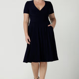 Fixed Wrap Bibi dress in Navy. Curvy size 12 woman wears a jersey dress the perfect corporate comfortable work dress. Below the knee length. Size 8 - 24.