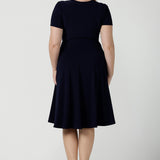 Back view of a fixed Wrap Bibi dress in Navy. Curvy size 12 woman wears a jersey dress the perfect corporate comfortable work dress. Below the knee length. Size 8 - 24.