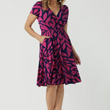 Bibi Fixed Wrap Dress in Pink Jungle. A pink and navy abstract print dress made in comfortable jersey fabric. Just below knee length with short sleeves. A v-neeckline. Designed for petite to plus size women -24. Designed and made in Australia. 