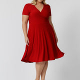 Plus sized woman wears red knee length dress made of cooling dry touch jersey fabric. Capturing the essence of the season, this sleeved dress is designed for women by woman in Australia and New Zealand. Available in sizes 8 to 24. Leina & Fleur ensure that there is a flattering fit for all.