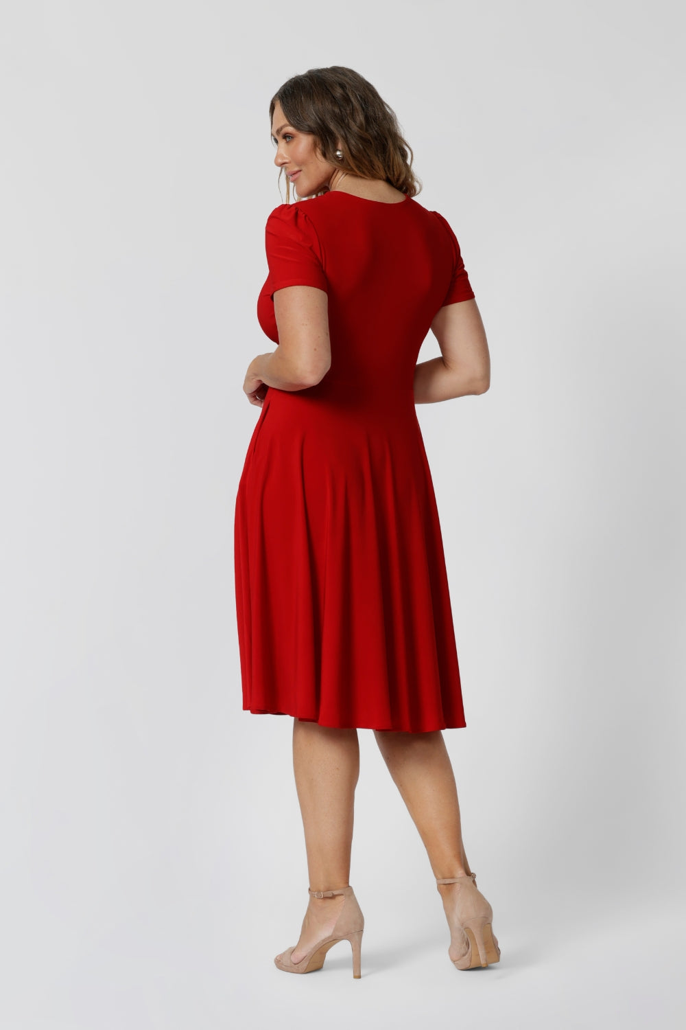 Back view of woman in red knee length dress. Plus sized woman wears red knee length dress made of cooling dry touch jersey fabric. Made for woman in Australia and New Zealand. Available in sizes 8 to 24. Leina & Fleur ensure that there is a flattering fit for all including plus & petite sizes.