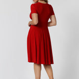 Back view of woman in red knee length dress. Plus sized woman wears red knee length dress made of cooling dry touch jersey fabric. Made for woman in Australia and New Zealand. Available in sizes 8 to 24. Leina & Fleur ensure that there is a flattering fit for all including plus & petite sizes.