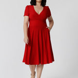 Petite woman wears fixed wrap dress. Sleeved dress is crafted from a soft, dry touch jersey fabric, making it both comfortable and stylish. Knee length dress is perfect for festive season with beautiful red standout colour. Leina & Fleur stocks this dress in sizes 8-24. 