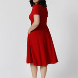 Back view of petite model wears knee length red dress. Sleeved dress is made from soft dry touch jersey fabric. This red dress has been designed with comfortability and style in mind. Knee length dress is perfect for festive season with its beautiful red standout colour. Leina & Fleur stocks Bibi Dresses in sizes 8-24 including both petite and plus sizes 