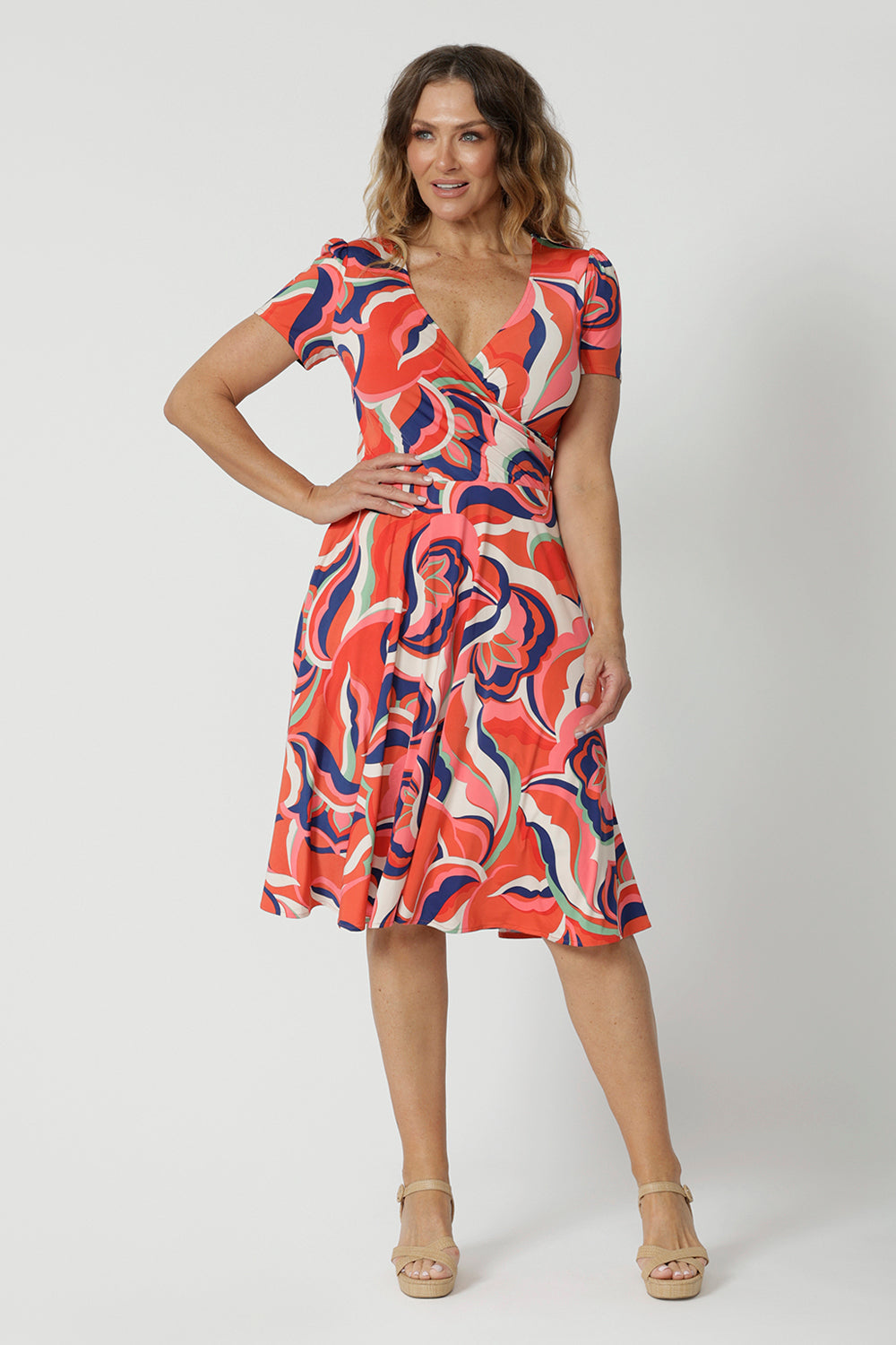 The best fixed wrap dress for over 50s women, the Bibi Wrap Dress is new in Tangerine, Red, White, Mint Green and Purple retro print. Shown on a size 12 woman, this summer wrap dress is a fit and flare style with full, knee length skirt and pockets. Easy-care, it's a good dress for travel and cruise wear. Made in Australia by Australian and New Zealand women's clothes brand Leina & Fleur.