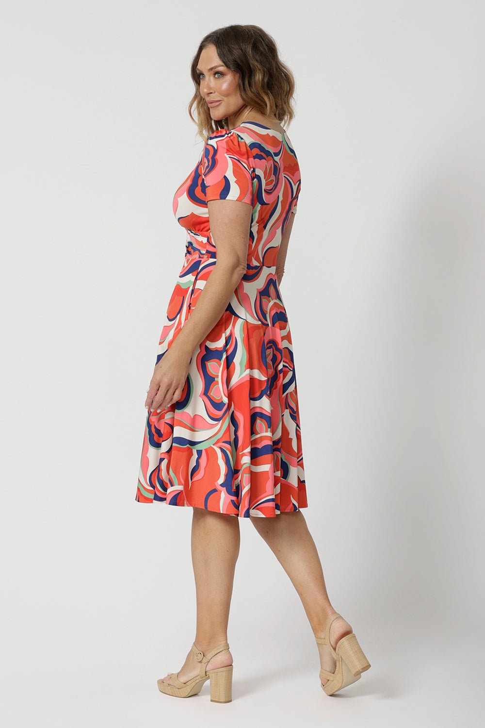 A good wrap dress for cruise wear, the Bibi Wrap Dress is summer ready in Tangerine, Red, White, Mint Green and Purple retro print. Shown on a size 12 woman, over 50s woman, this summer wrap dress is a fit and flare style with full, knee length skirt and pockets. Easy-care, it's a good dress for travel and cruise wear. Made in Australia by Australian and New Zealand women's clothes brand Leina & Fleur.