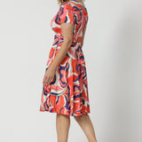 A good wrap dress for cruise wear, the Bibi Wrap Dress is summer ready in Tangerine, Red, White, Mint Green and Purple retro print. Shown on a size 12 woman, over 50s woman, this summer wrap dress is a fit and flare style with full, knee length skirt and pockets. Easy-care, it's a good dress for travel and cruise wear. Made in Australia by Australian and New Zealand women's clothes brand Leina & Fleur.