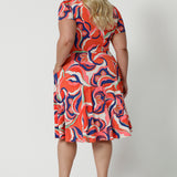 Back view of the best fixed wrap dress for plus size women. The Bibi Wrap Dress is new in Tangerine, Red, White, Mint Green and Purple retro print is shown on a curvy, size 18 woman. This plus size wrap dress is a fit and flare style with full, knee length skirt and pockets. With short sleeves it's a good summer dress. Made in Australia by Australian and New Zealand women's clothes brand Leina & Fleur.