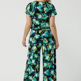 Size 12 woman wears the Dany culotte in Canopy, a wide leg culotte with the canopy print. A bold green colour splatter print. Styled back with nude heels and the Bowie Top in Canopy. Made in Australia for women size 8 - 24. 