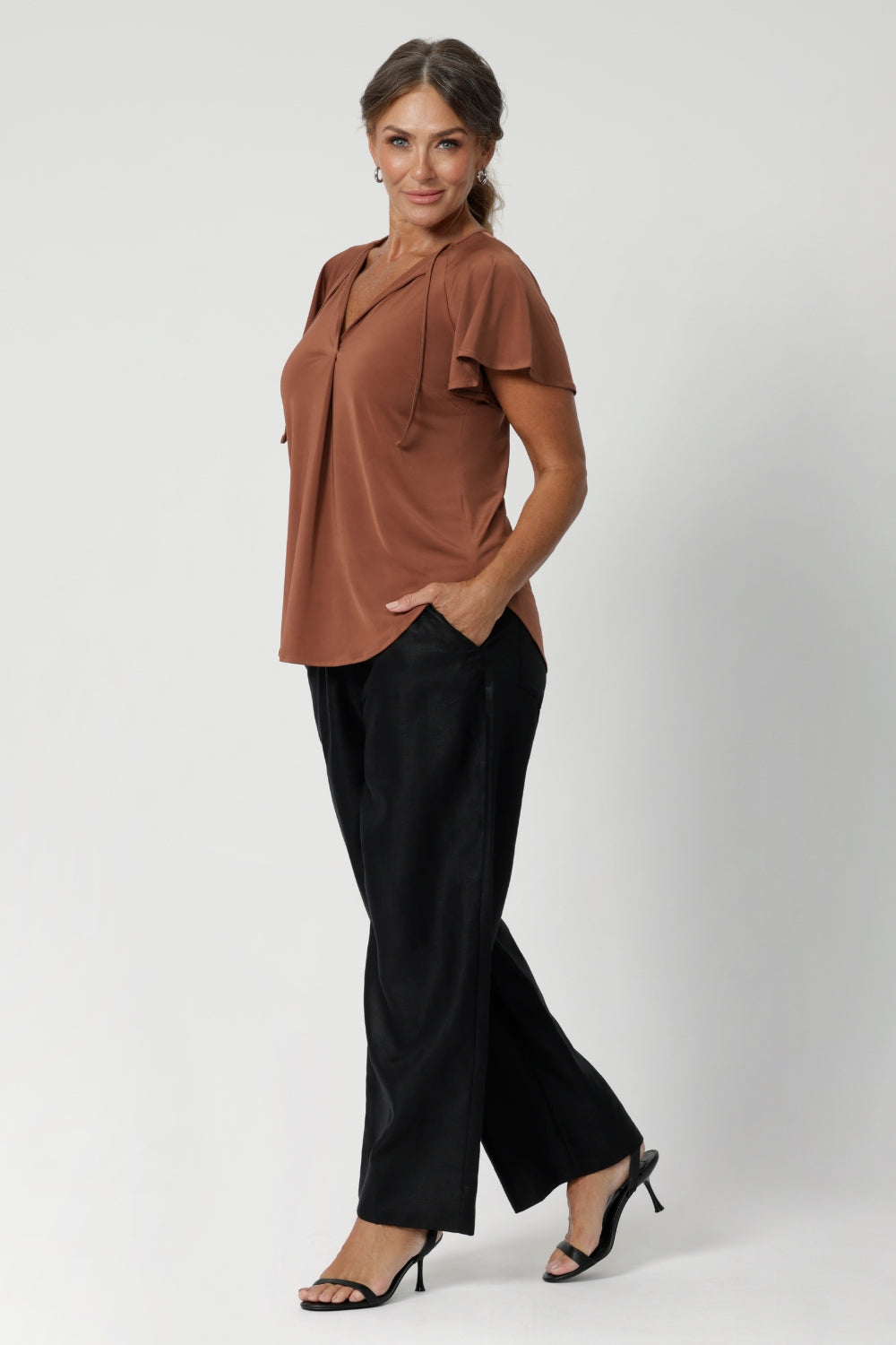 V-neckline is complemented by delicate thin fabric ties that can be left loose for a relaxed vibe or tied for a more vintage-inspired feel. A centre-front pleat adds structure and sophistication, elevating the overall design.