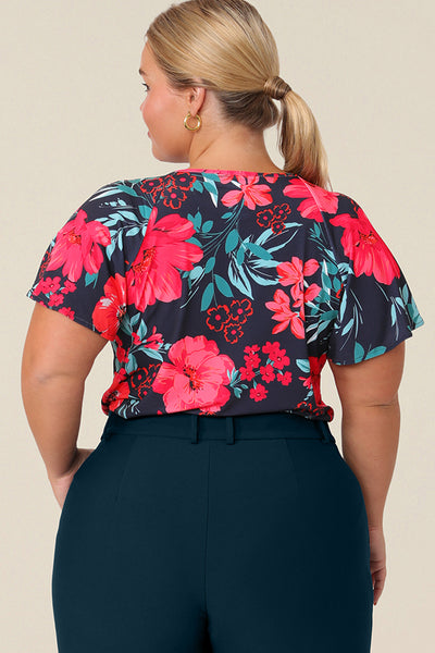 Back view of a plus size, size 14 woman wearing a casual jersey top. The top has short raglan sleeves, a V-neckline and is printed with a floral pattern for a casual weekend look.