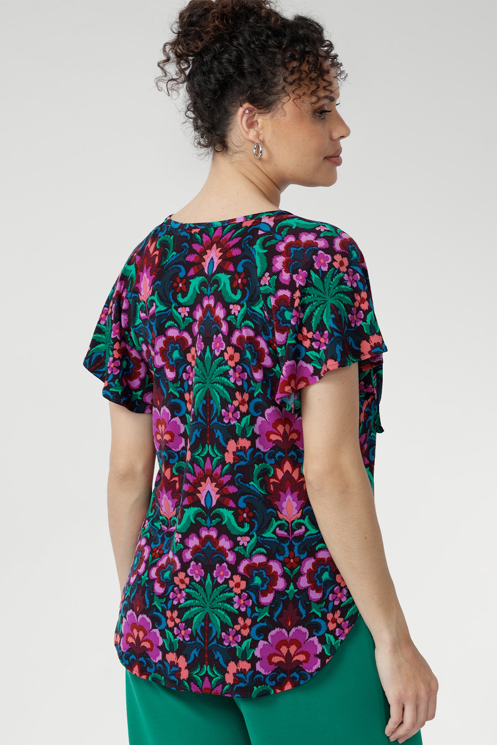 Thoughtful details like the centre-front pleat, raglan shoulders, short flutter sleeves, and a curved shirt-tail hemline create a beautifully balanced silhouette that suits a variety of body shapes.