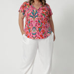 Plus sized model wears flattering V-neck top with delicate thin ties that can be adjusted for a customisable fit. Easy care fabric is on a tropical abstract print, made from lightweight crepe jersey. Providing breathability and comfortability. Shop this ideal summer top in sizes 8-24. 