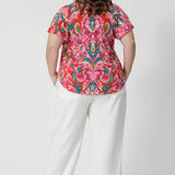 Back view of plus sized wearing summer ready top with shirttail hemline that can be adjusted for a customisable fit. Easy care fabric is on a tropical abstract print, made from lightweight crepe jersey. Shop this breathable and comfortable summer top in sizes 8-24. 