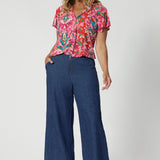Flutter sleeved summer top offers a relaxed fit that drapes beautifully with v neck and shirt tail hemline features. Ideal piece for staying cool and stylish during the summer months. Model pairs printed blouse with denim pants to create a casual day look. This top is comes in sizes 8-24, made by Leina & Fleur